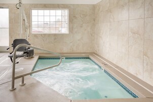 Un área de spa con un jacuzzi, una ventana y una silla.