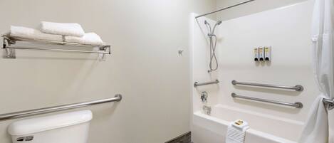 A bathroom with a white toilet, a bathtub with a shower, and a towel rack with towels.
