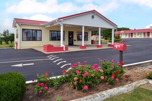 A motel with a covered front porch, a mailbox, and a parking lot.