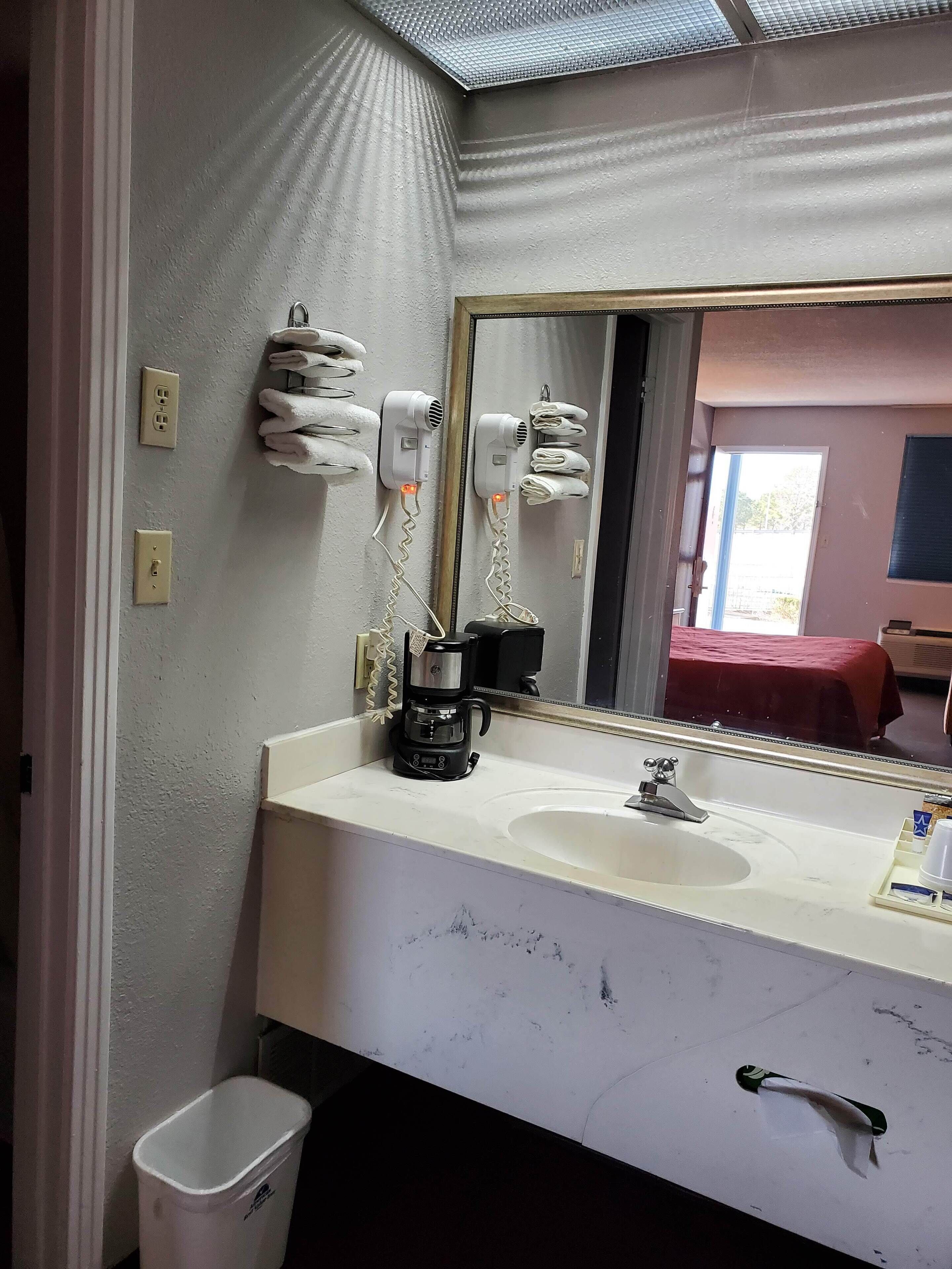 A bathroom with a white sink, a mirror, and two hair dryers mounted on the wall.