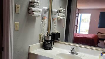 A bathroom with a white sink, a mirror, and two hair dryers mounted on the wall.