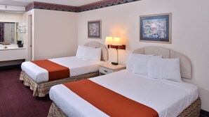 Een hotelkamer met twee bedden, een nachtkastje met een lamp, een schilderij aan de muur en een zichtbare badkamer op de achtergrond.