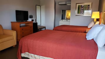 Une chambre d’hôtel avec un grand lit, un téléviseur posé sur une commode en bois, un petit bureau et un miroir.