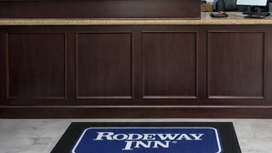 A reception desk at Rodeway Inn with a welcome sign, informational posters, and a clock on the wall. - Rodeway Inn Killeen near Fort Hood (Killeen)