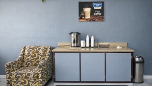 A kitchenette with a patterned armchair, a coffee machine, and a trash can. - Rodeway Inn Killeen near Fort Hood (Killeen)