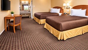 A hotel room with two beds, a desk, a chair, a TV, and a bathroom visible through an open door. - Rodeway Inn Killeen near Fort Hood (Killeen)
