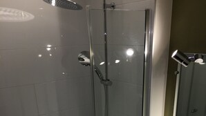 Un baño moderno con ducha de vidrio, lavamanos blanco y espejo sobre el lavamanos.