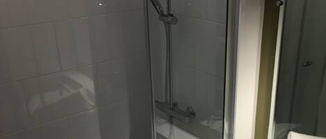 Ein modernes Badezimmer mit einer begehbaren Glasdusche, einem weißen Waschbecken und einem Spiegel darüber.