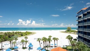 A beach view with a hotel in the foreground, palm trees, and beach umbrellas. - Clearwater Beach Sheraton Resort on Sand Key (Clearwater Beach)