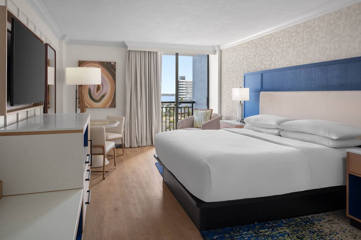 A hotel room with a large bed, a desk, a chair, and a TV.