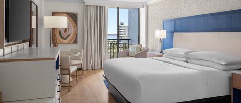 Una habitación de hotel con una cama grande, un escritorio, una silla y un televisor.
