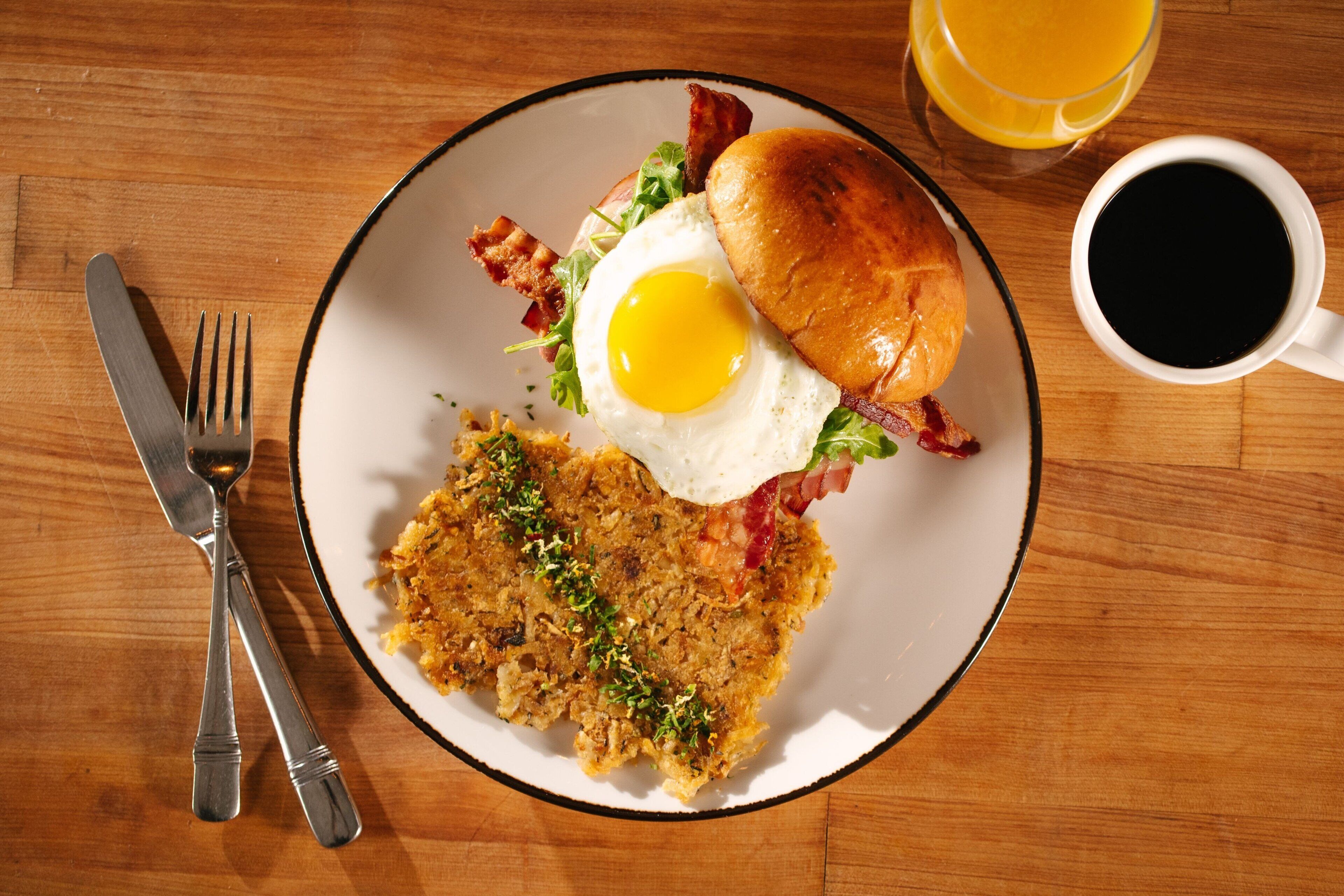 A breakfast plate with eggs, bacon, and hash browns on a wooden table.