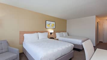 Habitación de hotel con dos camas, un escritorio, una silla y un sofá.