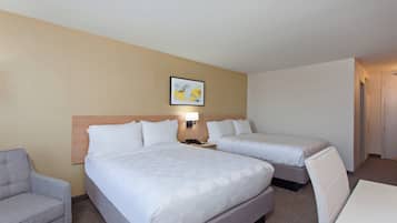 Habitación de hotel con dos camas, un escritorio, una silla, una lámpara y un cuadro en la pared.