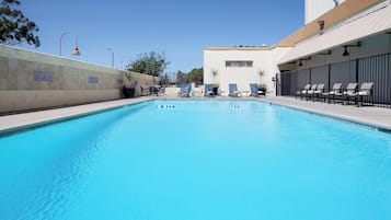 Ein Schwimmbecken mit Liegestühlen und einem Gebäude im Hintergrund.