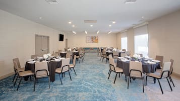 A conference room with multiple tables, chairs, and a carpeted floor.