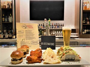 Eine Barbereich mit einer Speisekarte, einem Bierglas und Speisen wie Burgern und Tacos.