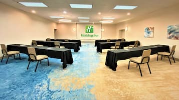 A conference room with tables and chairs, Holiday Inn logo, and artwork on the wall.