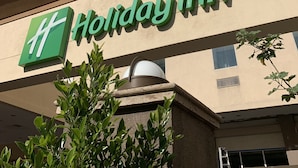 Un bâtiment d’hôtel Holiday Inn avec une façade beige, de nombreuses fenêtres et un logo vert bien visible.
