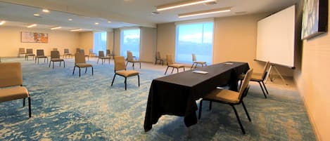 A conference room with a long table, chairs, a whiteboard, and large windows.