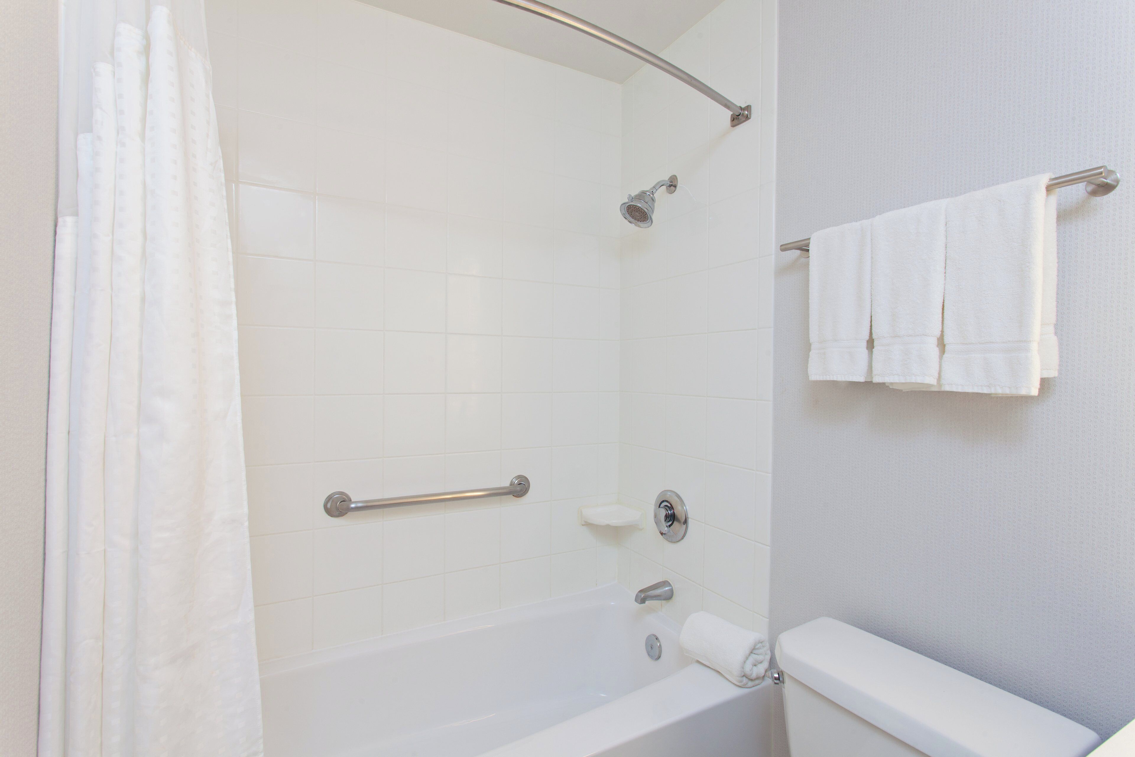 A bathroom with a bathtub, a shower, a toilet, and a towel rack.