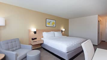 A hotel room with a bed, a sofa, a small table, and a chair.