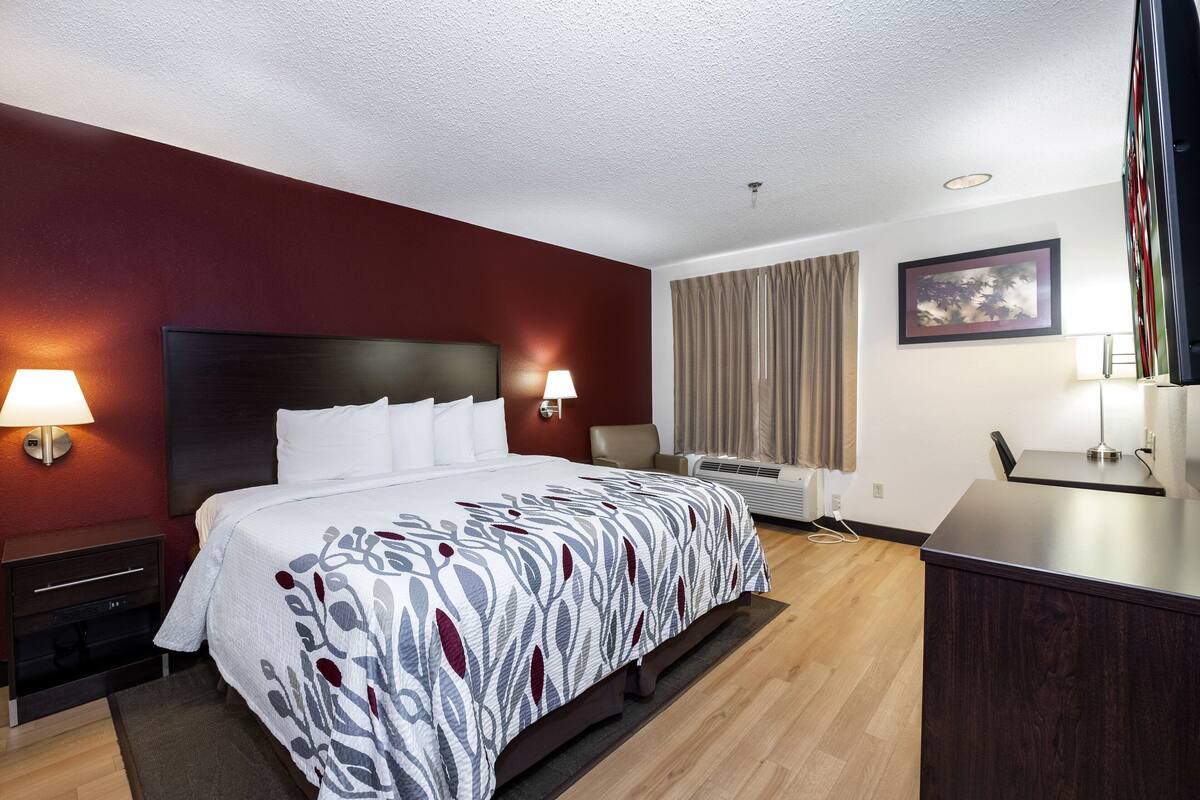Une chambre d’hôtel avec un grand lit, deux lampes de chevet, un bureau et une chaise.