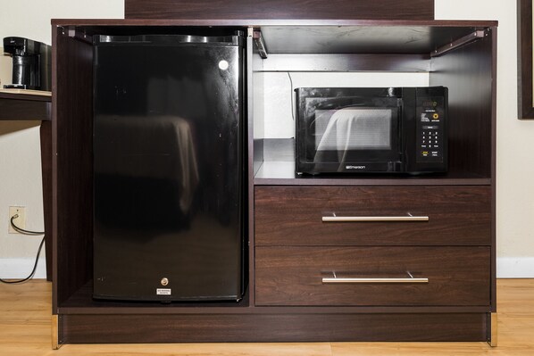 A compact kitchen with a refrigerator and a microwave on a wooden cabinet. - Red Roof Inn Knoxville Central - Papermill Road (Knoxville)