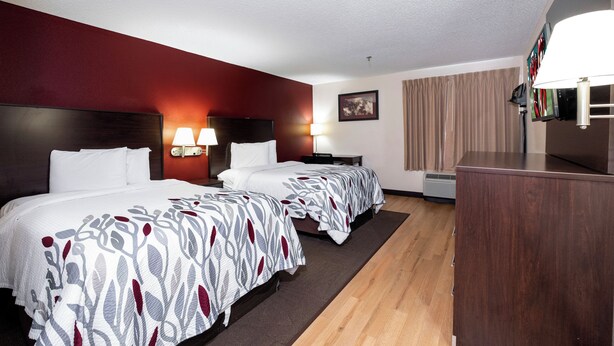 A hotel room with two beds, a desk, a TV, and a large window with curtains. - Red Roof Inn Knoxville Central - Papermill Road (Knoxville)