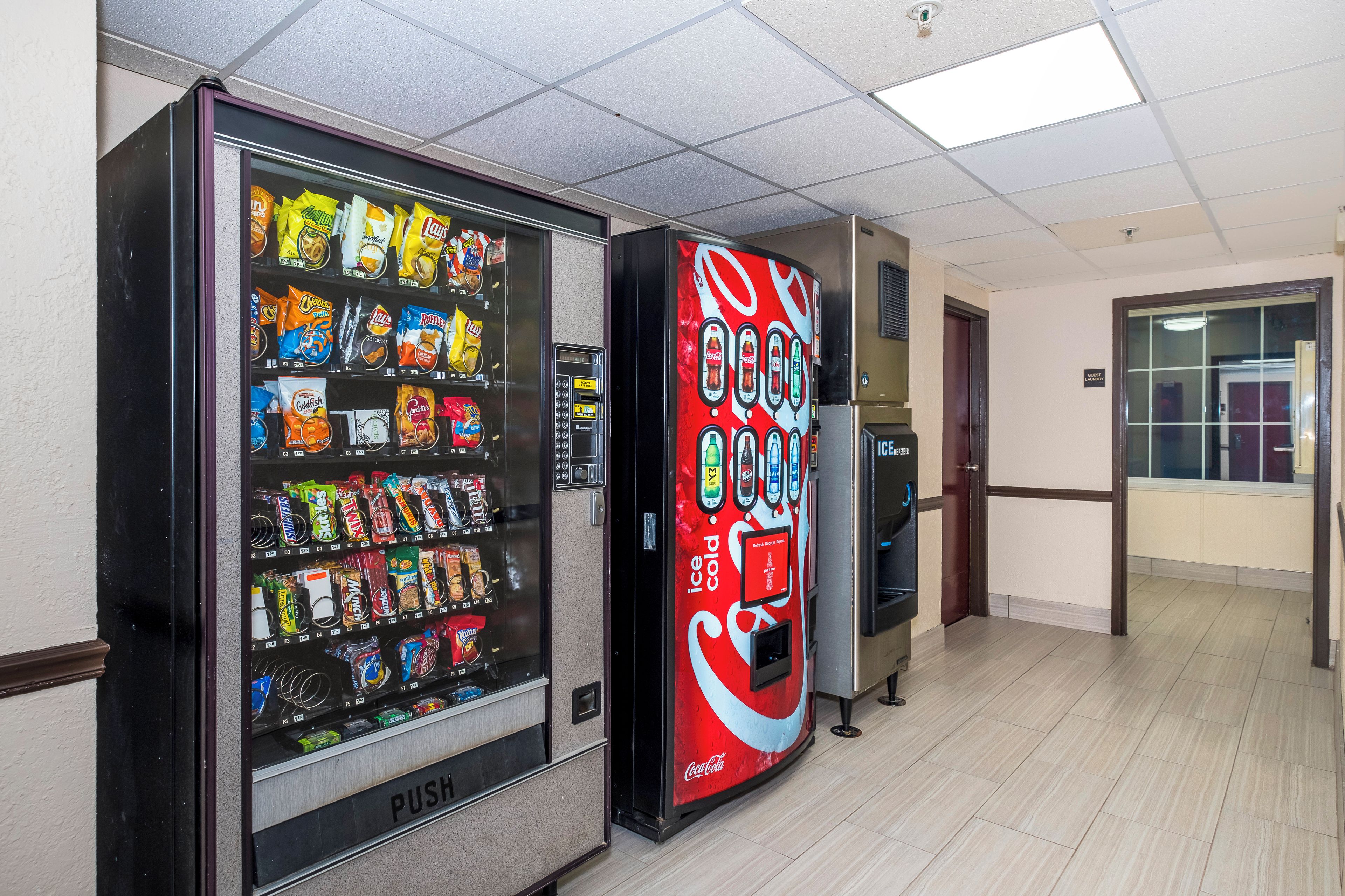 A vending machine with snacks and a Coca-Cola dispenser in a hallway.