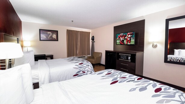 A hotel room with two beds, a desk, a chair, a television, and a mirror. - Red Roof Inn Knoxville Central - Papermill Road (Knoxville)