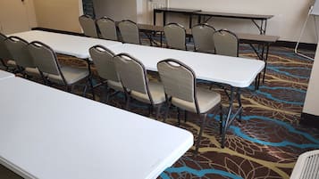 A conference room with tables and chairs, carpeted floor, and ceiling lights.