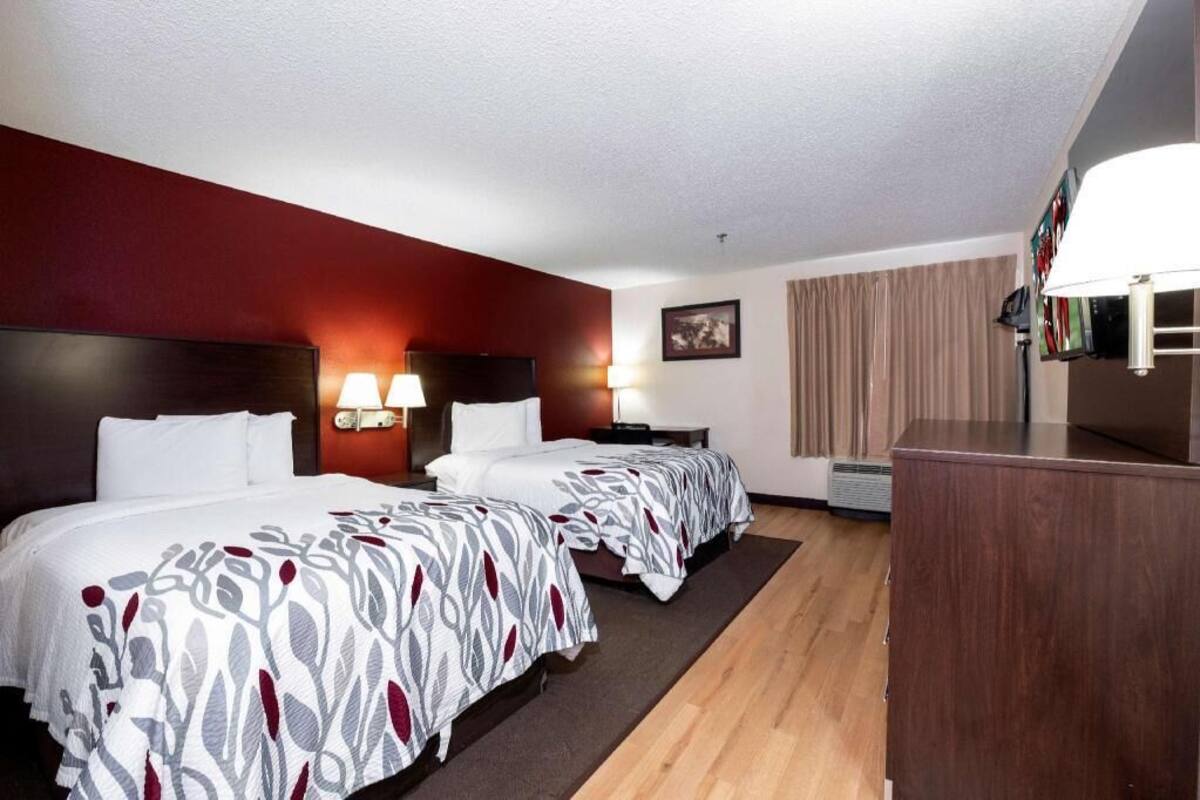 Une chambre d’hôtel avec deux lits, un bureau, une télévision et une lampe.