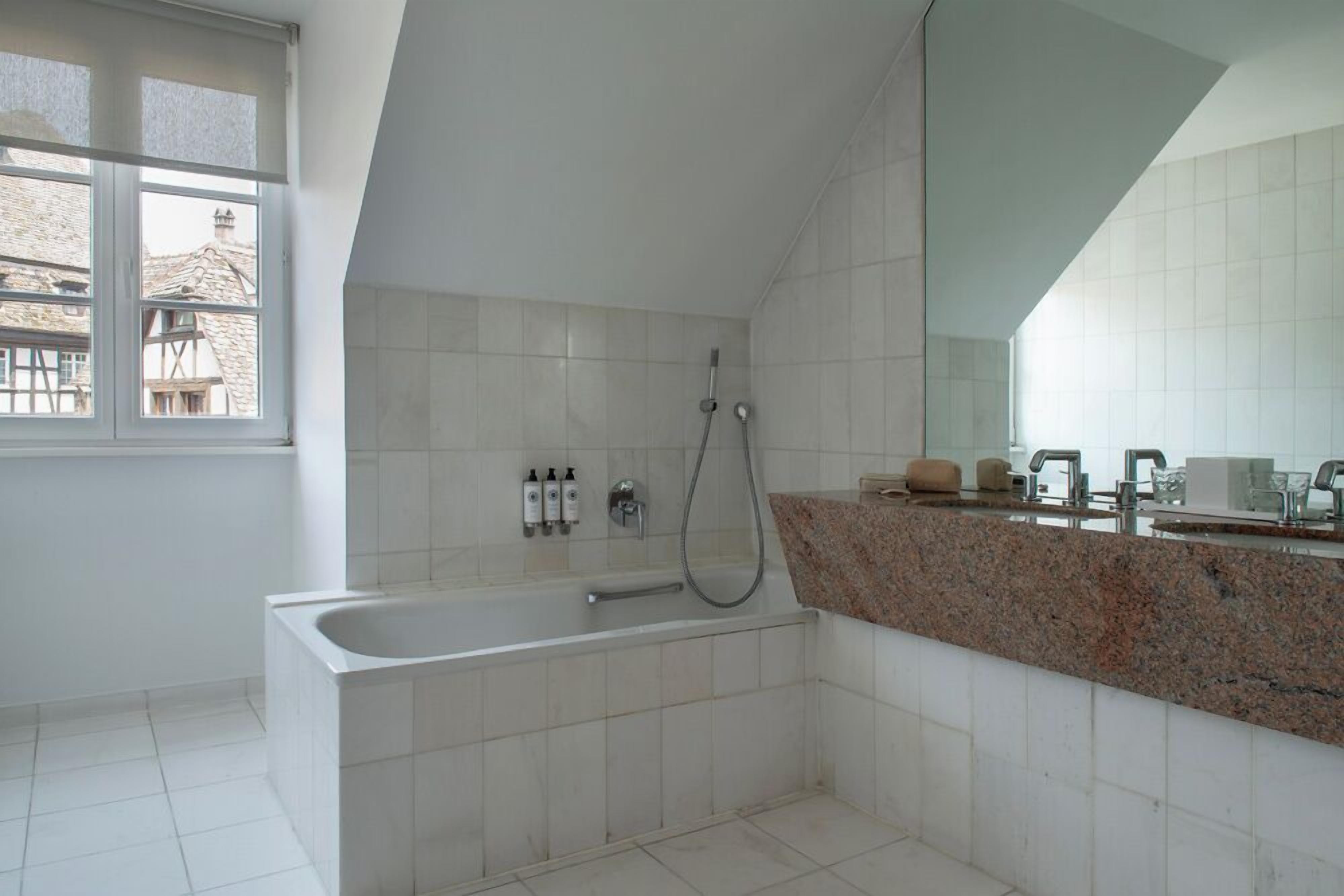 A modern bathroom with a freestanding bathtub, a shower, and a granite countertop with a sink.