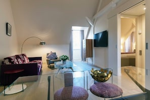 A modern living room with a sofa, armchair, and glass coffee table.