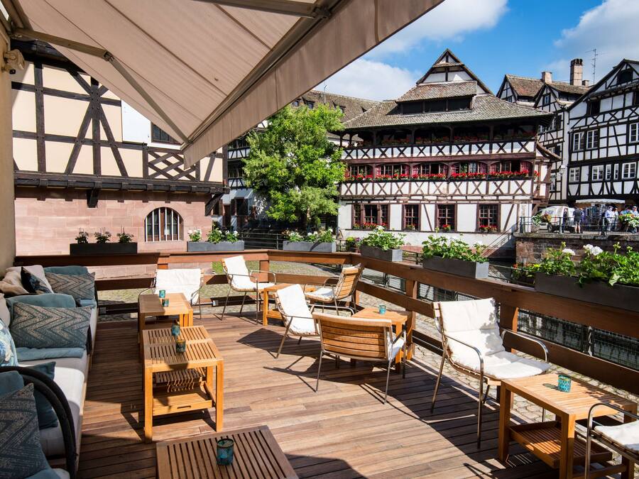 An outdoor seating area with wooden furniture and a view of traditional half-timbered buildings.