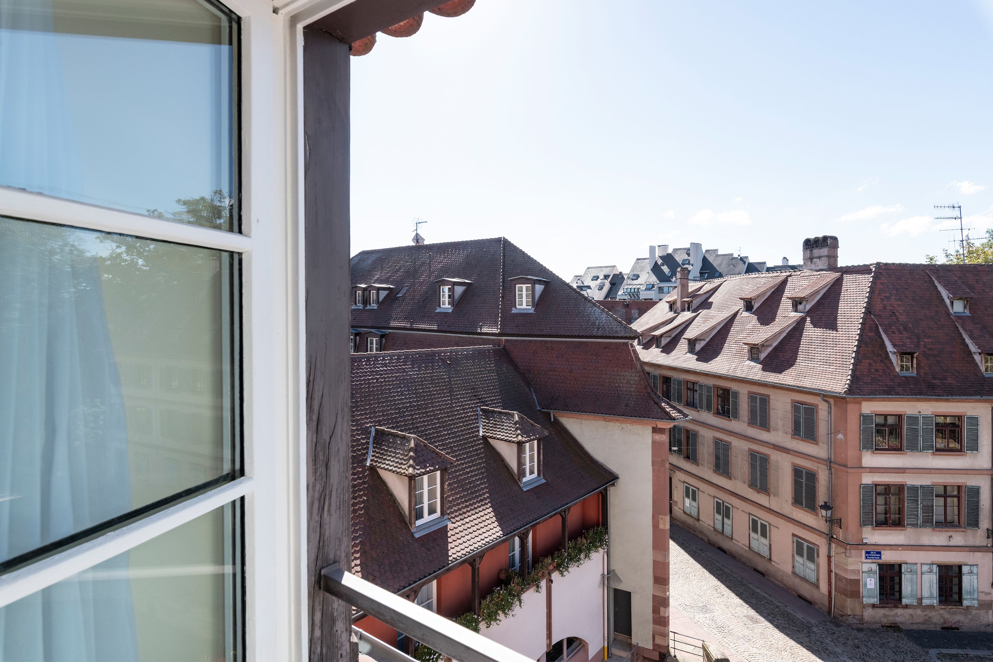 A view from a window overlooking traditional European-style buildings with multiple stories, steeply pitched roofs, and dormer windows.