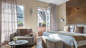 Une chambre d’hôtel avec un canapé, un lit, une petite table avec un vase et une vue sur l’extérieur.