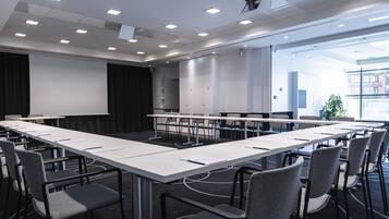 Un salón de conferencias con una larga mesa, sillas y una pantalla para proyector.