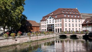 Un hôtel historique de style architectural européen traditionnel, caractérisé par une entrée imposante et un pont enjambant un canal.