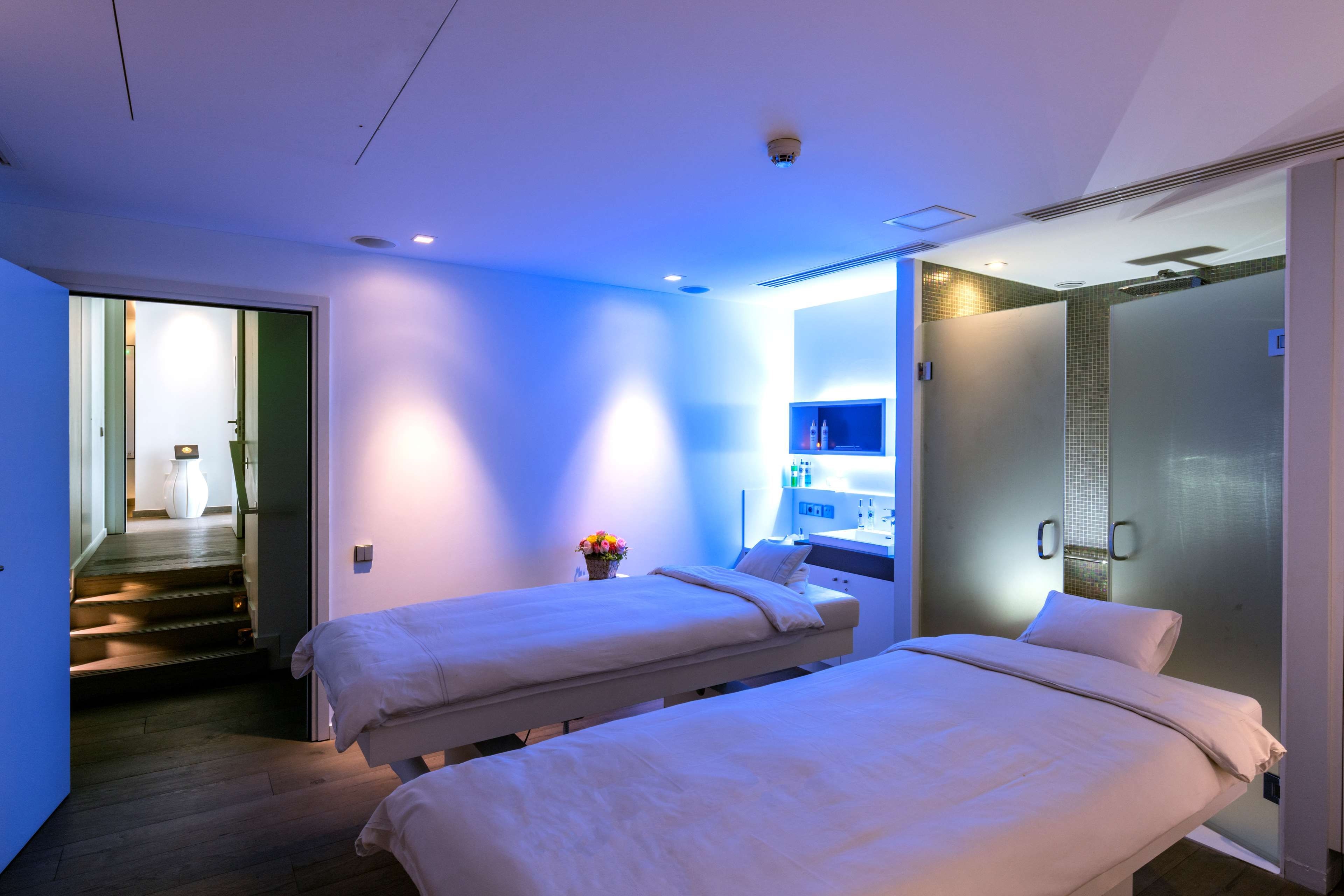 Een hotelkamer met twee bedden, een badkamer en een klein zithoekje met een bloevas.