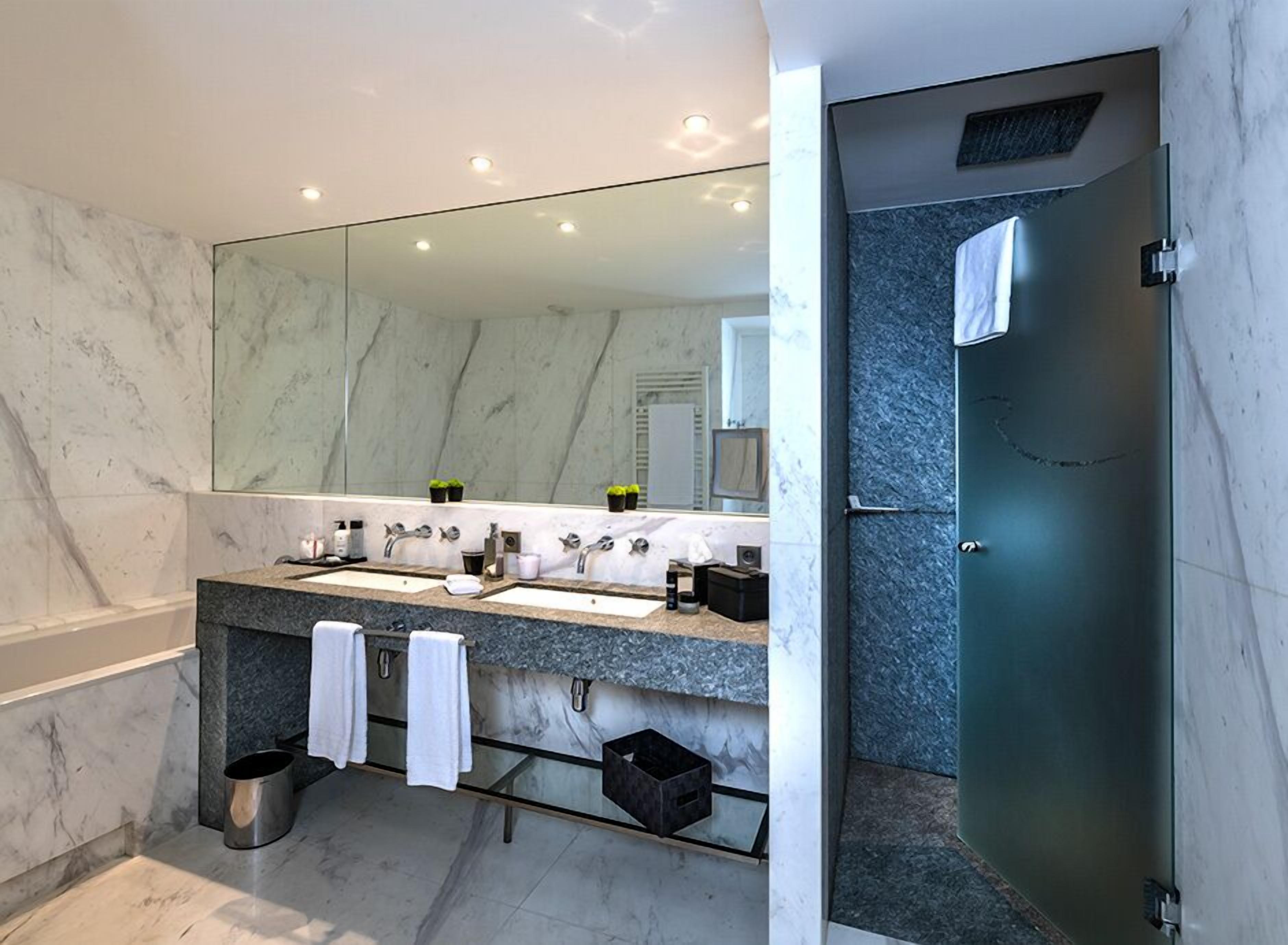 A modern bathroom with a dual sink vanity, a large mirror, and a glass-enclosed shower.