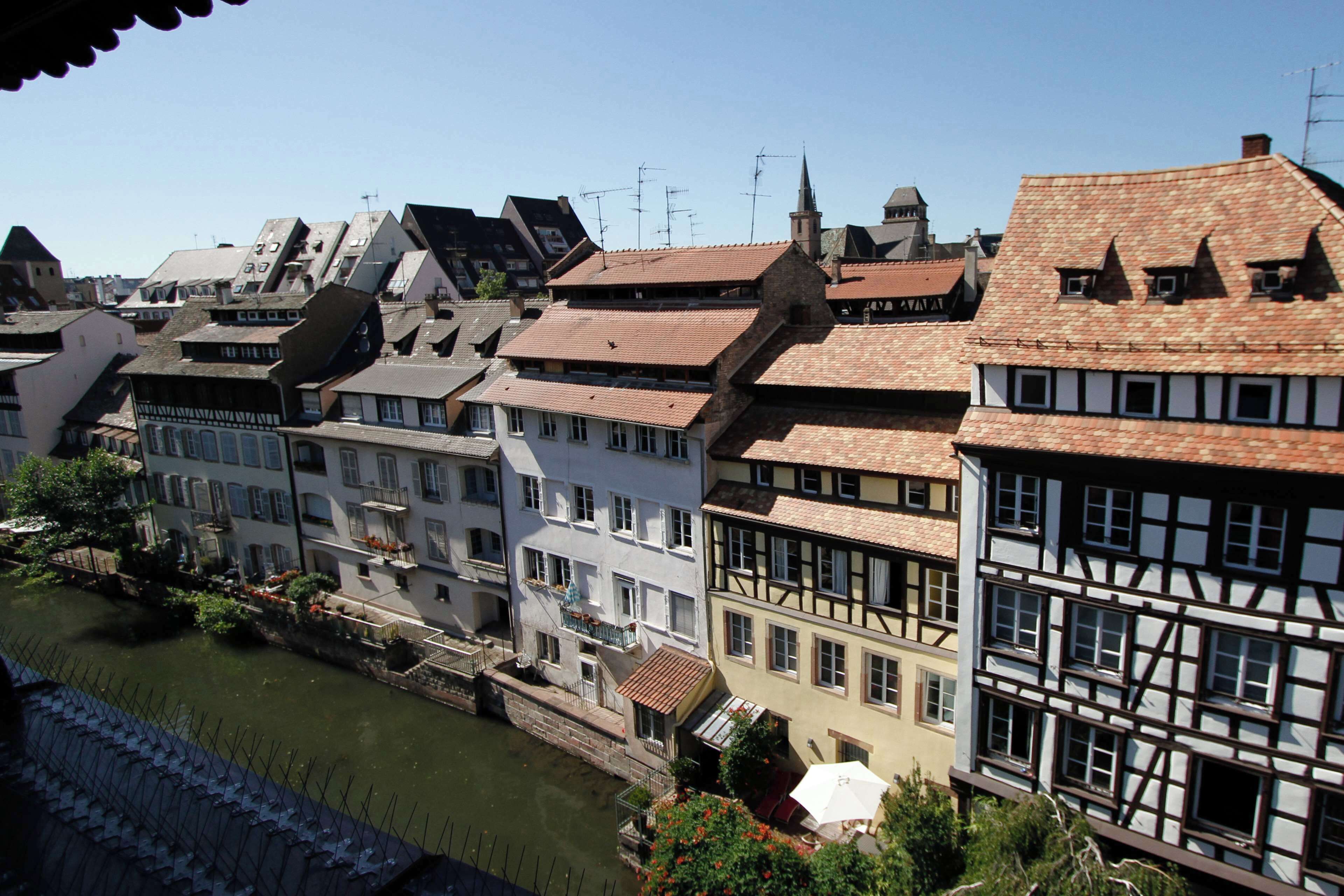 Eine Reihe traditioneller europäischer Gebäude mit steilen Satteldächern und einem Fluss im Vordergrund.