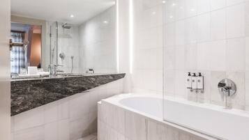 A modern bathroom with a large mirror, a freestanding bathtub, and a shower area.