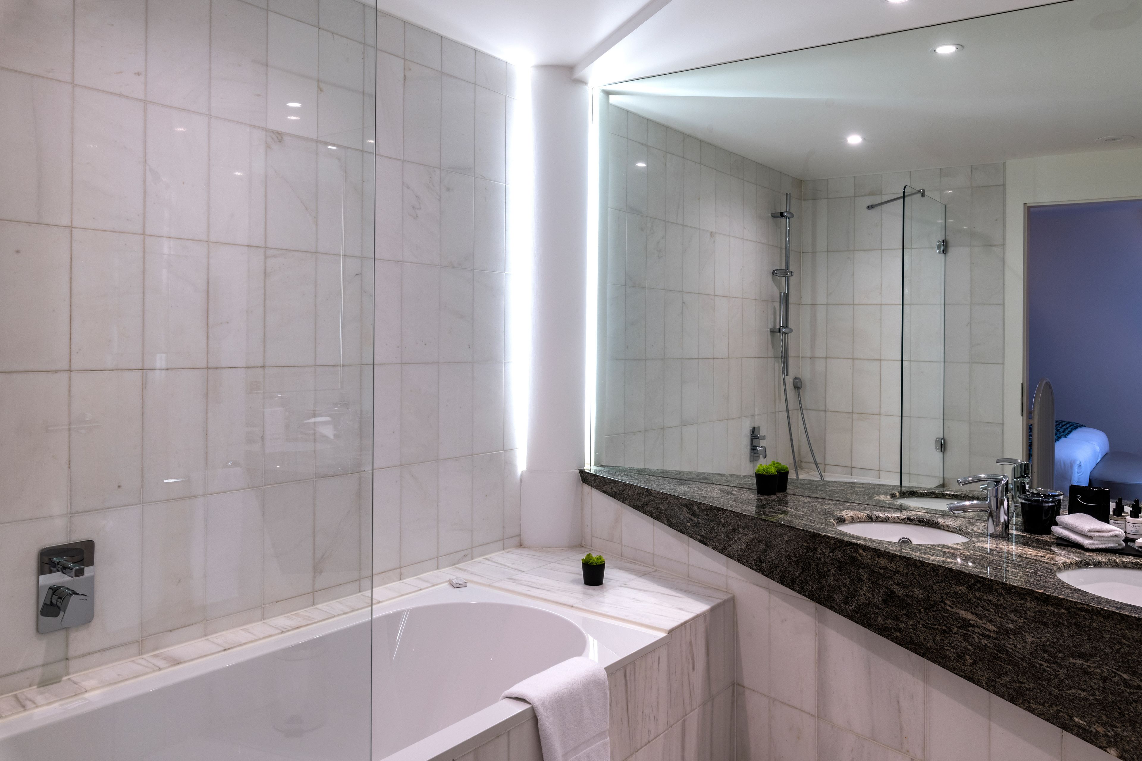 A modern bathroom with a large mirror, a bathtub, and a shower area.