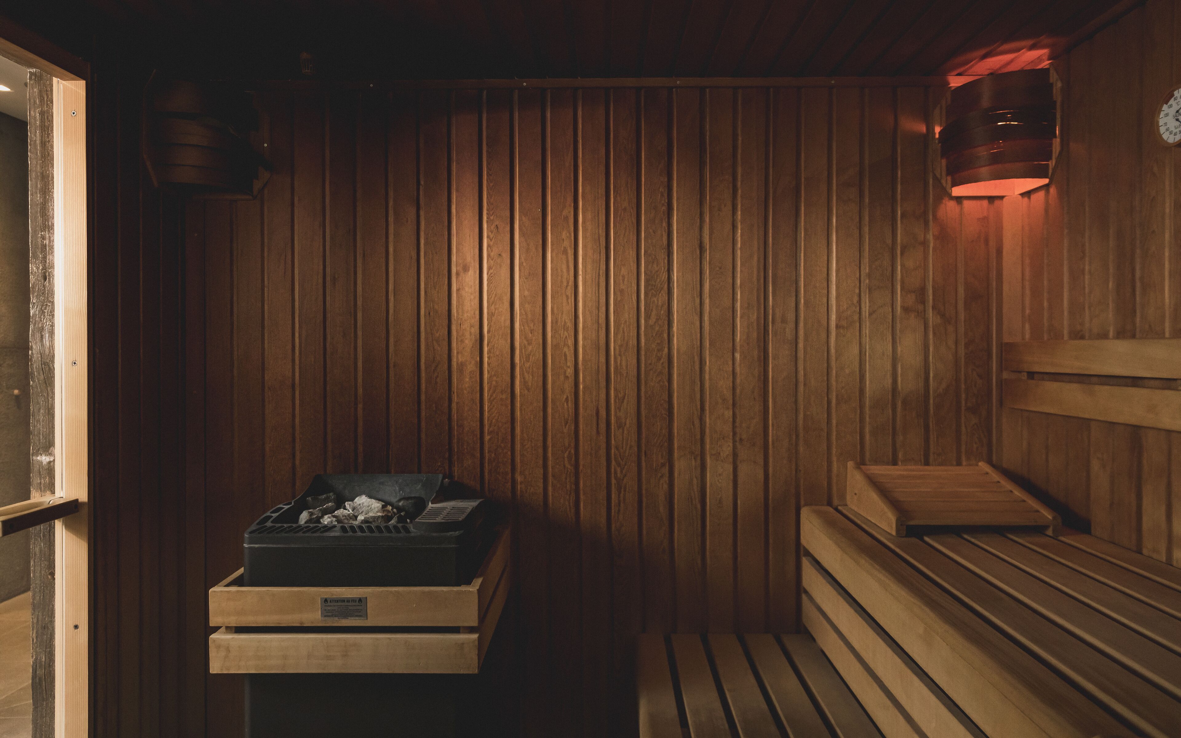 A sauna room with wooden walls, benches, and a heater.