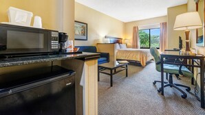A hotel room with a kitchenette, a bed, a desk, and a chair. - Mi Casa Hotel (Orlando)