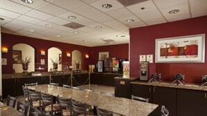 A hotel dining area with granite tables and chairs, a kitchen counter, and a framed artwork on the wall. - Mi Casa Hotel (Orlando)