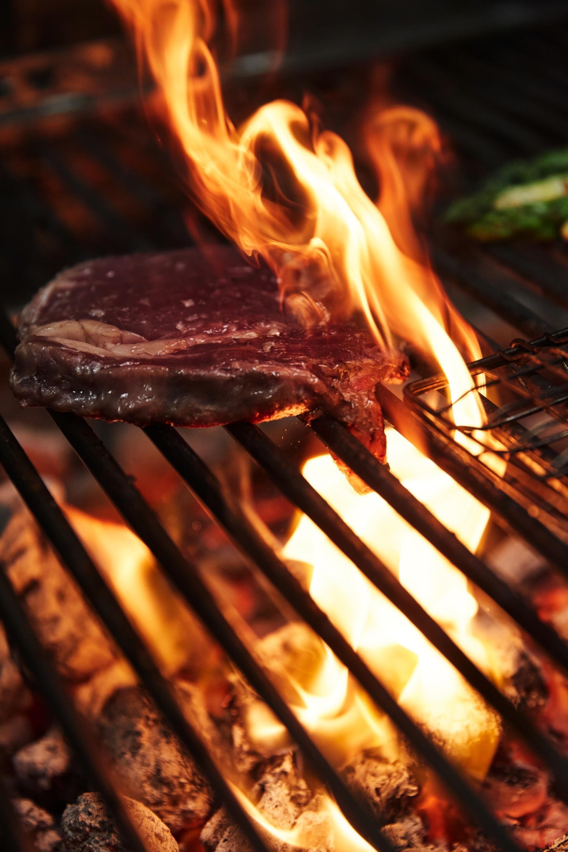 A steak grilling over an open flame.