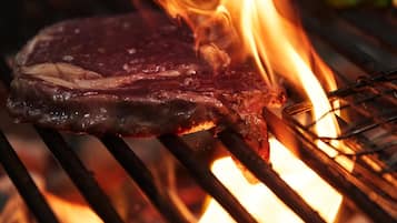 A steak grilling over an open flame.